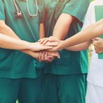 Cooperation of people in the medical community with a hands together between the doctor in the green suit and nurses in white dress to comment provide the most effective treatment to patients outdoor.